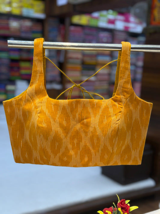 Handloom yellow ikkat padded blouse with broad straps and back hook closure – perfect for sarees and ethnic wear.